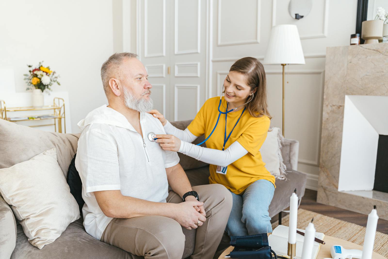 Medicare Supplement, A nurse uses a stethoscope for a home check-up on a senior adult in a cozy living room.